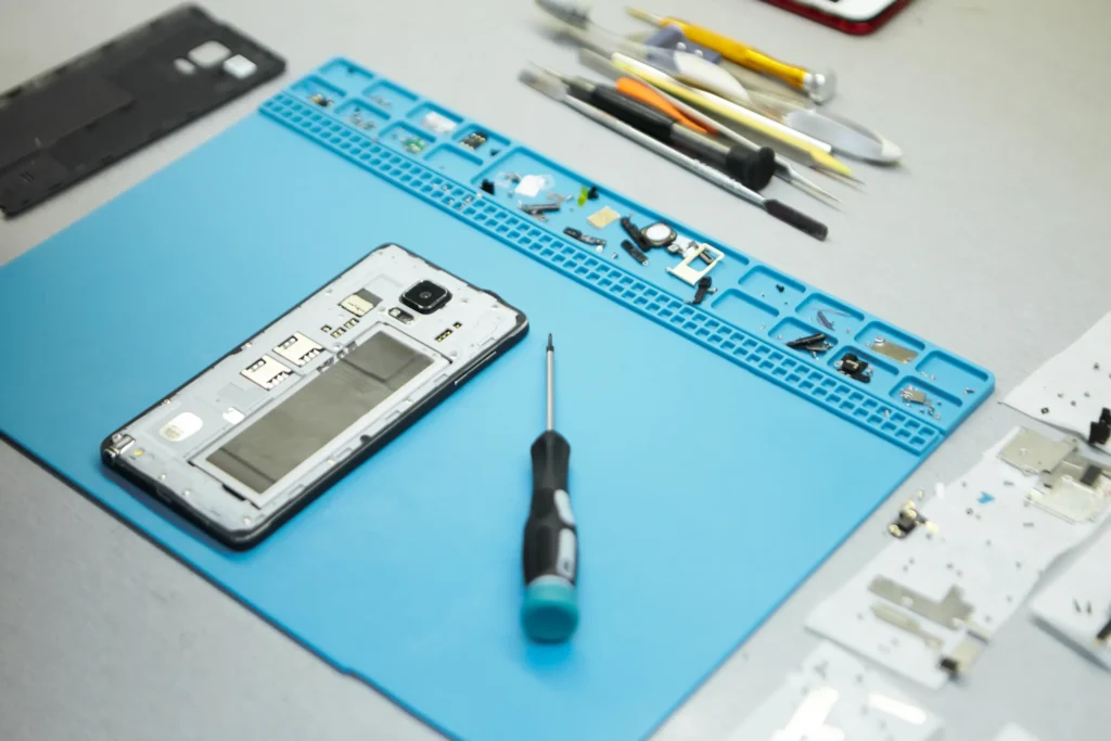 Can a Professional Service Fix What a DIY Mobile Repair Might Miss? 1 DIY mobile repair setup with disassembled smartphone, screwdriver, and repair tools on a blue mat